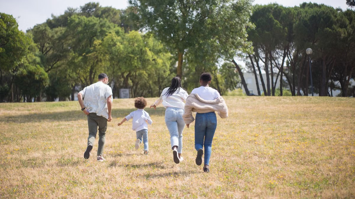 Cheerful family walking together in a sunny park surrounded by trees.